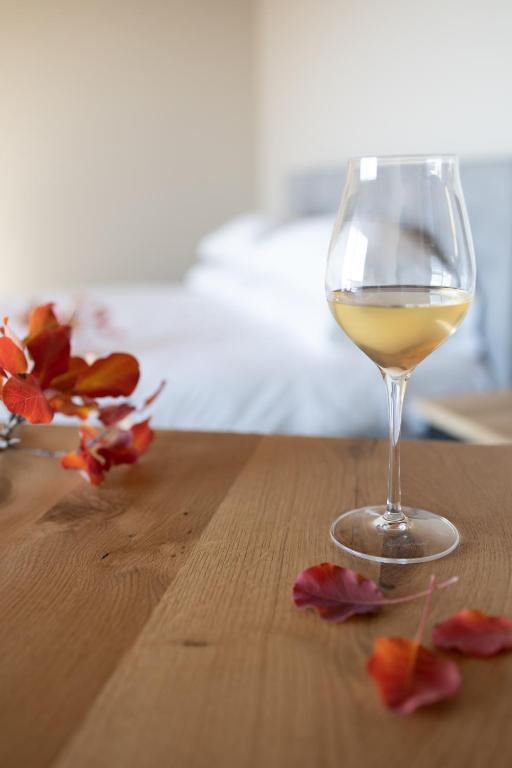 a glass of white wine sitting on a wooden table at Encanto Agriturismo & Private SPA in Visogliano