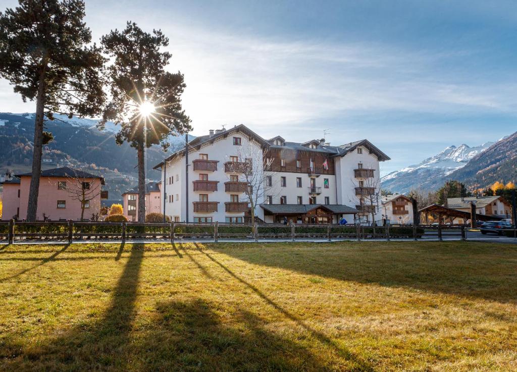 a group of buildings in a field with mountains in the background at Hotel Villa Rina in Bormio