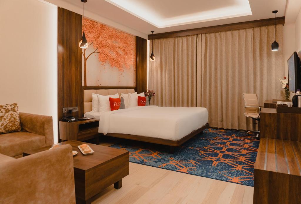 a hotel room with a bed and a desk and a couch at Playotel Premier Vijay Nagar in Indore