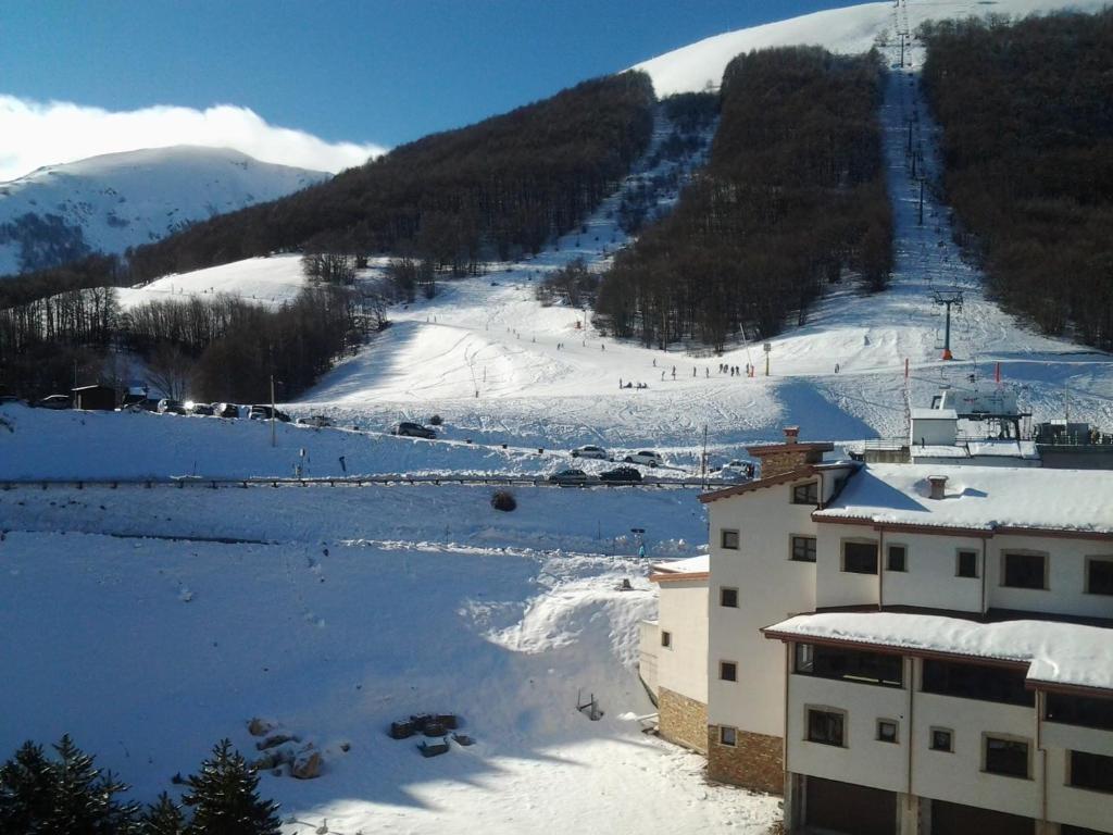 una montaña cubierta de nieve con una pista de esquí y un edificio en Monolocale Residence Paradiso Aremogna a due passi dagli impianti sciistici, en Roccaraso