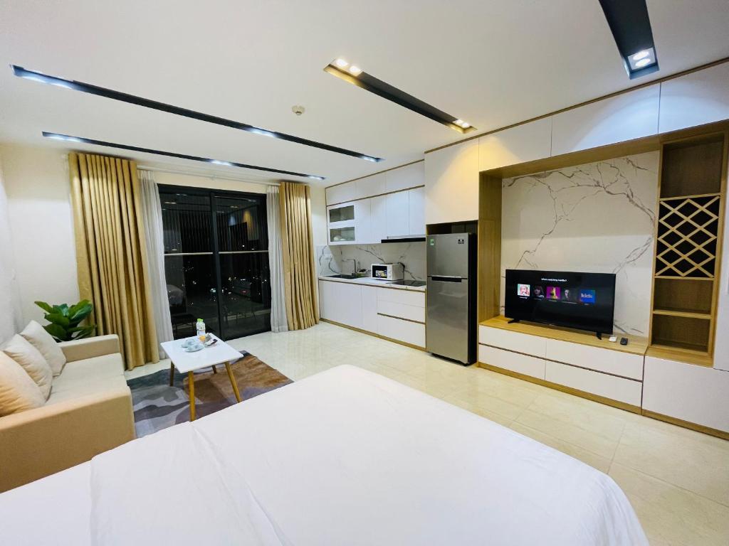 uma sala de estar com uma cama branca e uma cozinha em Gavi Home - Luxury Apartment D'Capitale Trần Duy Hưng Hà Nội em Hanói