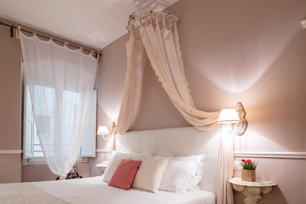 una camera da letto con un letto bianco con tende bianche di B&B Emozioni Fiorentine a Firenze