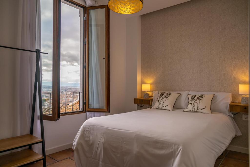 a bedroom with a white bed and a large window at Florentia San Nicolás in Granada