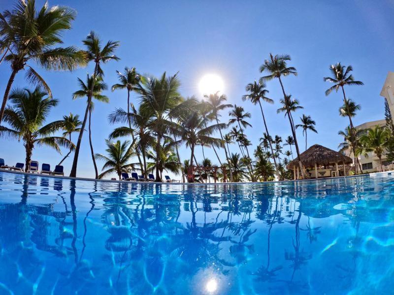 una grande piscina con palme sullo sfondo di Villa Mar, Juan Dolio a Juan Dolio