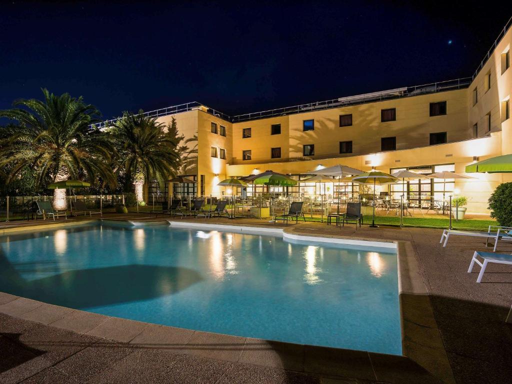 uma piscina em frente a um hotel à noite em Mercure Cannes Mandelieu em Cannes