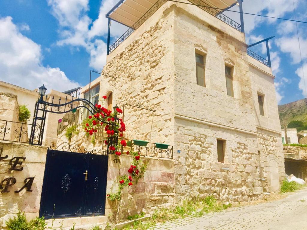 a stone building with a blue door and flowers on it at Monte Cappa Cave House in Urgup