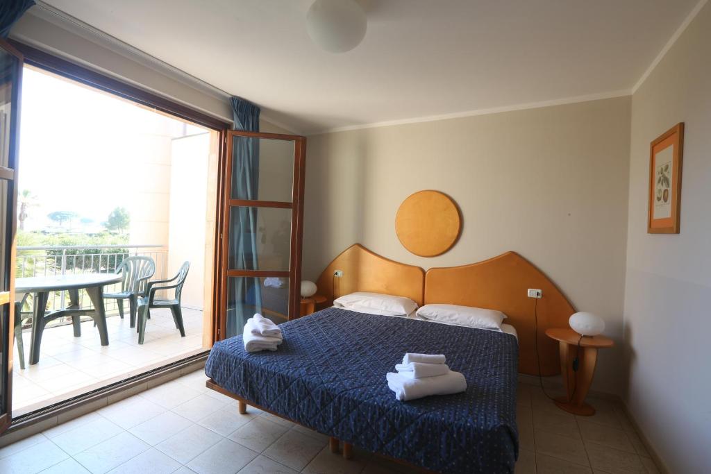 a bedroom with a bed and a balcony with a table at Cosmopolitan Golf & Beach Resort in Tirrenia