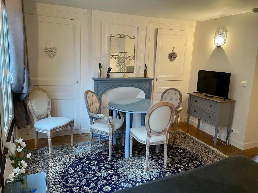 ein Wohnzimmer mit einem Tisch, Stühlen und einem TV in der Unterkunft LA PARENTHÈSE DU CAPUCIN in Honfleur