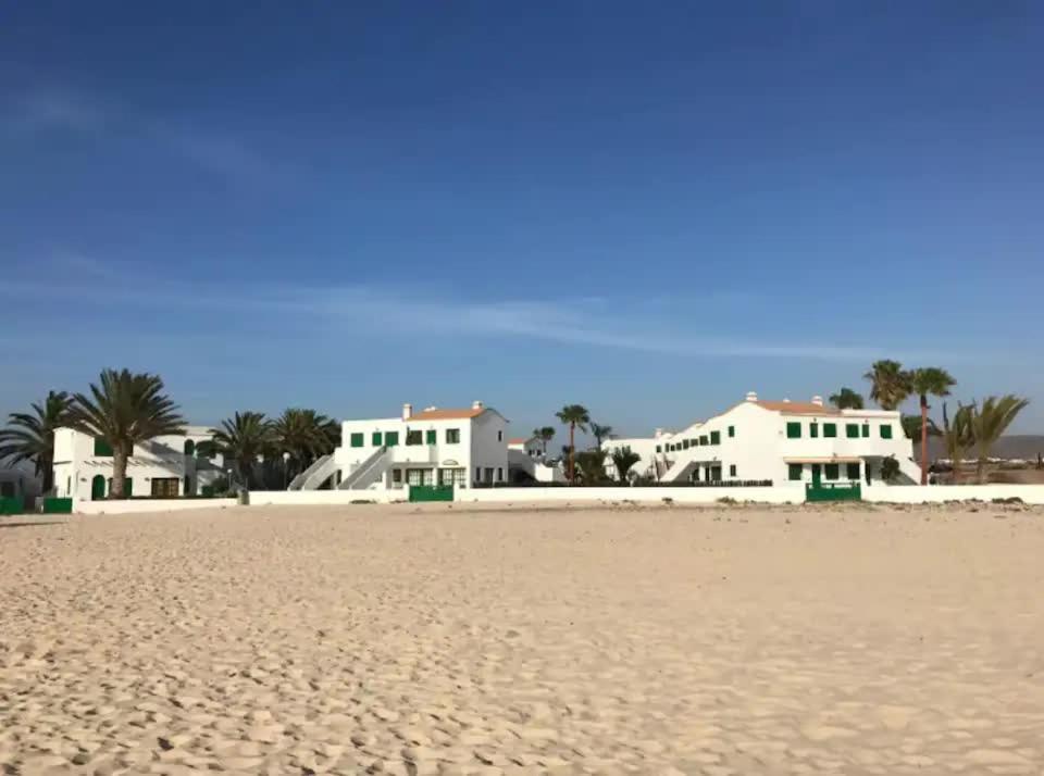 Blick auf den Strand mit Häusern im Hintergrund in der Unterkunft El Sueño - Appartamento fronte spiaggia vista mare in Cotillo
