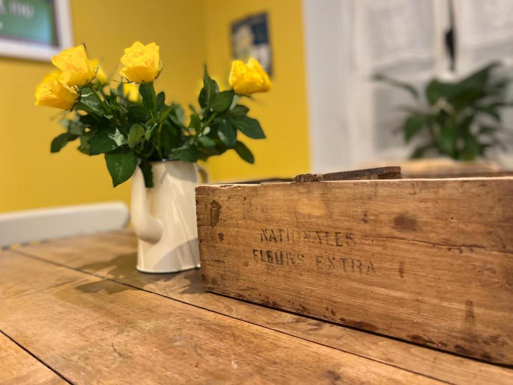 a vase of yellow roses on a wooden table at Maison Père in Lagarde