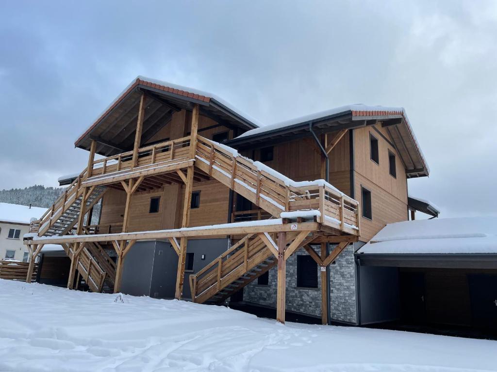 une grande maison en bois avec une terrasse dans la neige dans l'établissement Résidence les biches, à Xonrupt-Longemer
