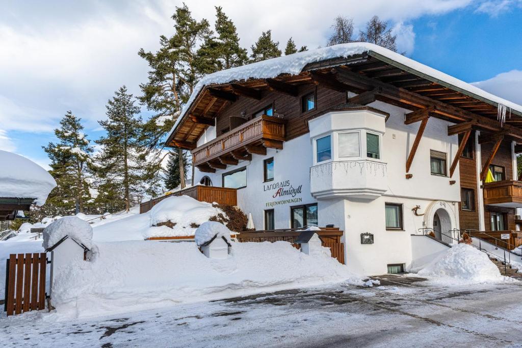 una casa cubierta de nieve con árboles en el fondo en Appartement Rianne/Landhaus Almidyll, en Seefeld in Tirol
