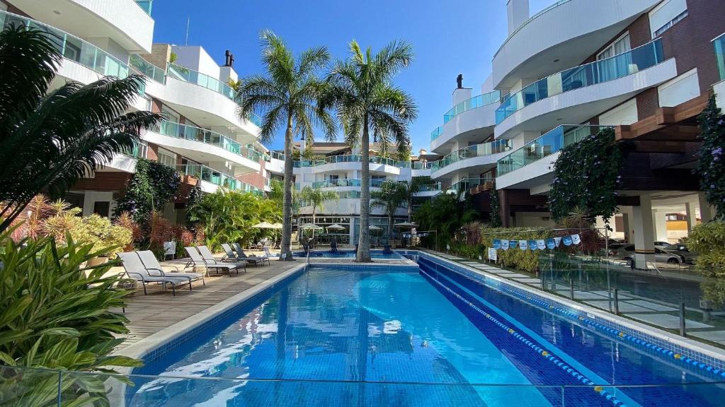 una piscina frente a un edificio con palmeras en Boulevard Bombinhas - Um condomínio Completo que vai te encantar, en Bombinhas