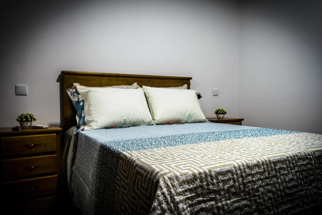 a bedroom with a bed with two pillows and a dresser at Hostel Encostas Do Douro in Marco de Canaveses