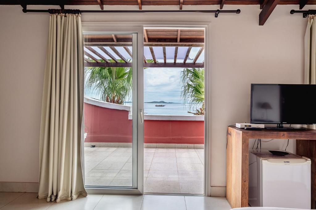 um quarto com uma porta de vidro deslizante e vista para o oceano em Mata Hari Apartamentos em Búzios
