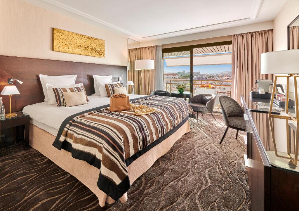 カンヌにあるホテル バリエール ル グレイ ダルビオンのベッドとデスクが備わるホテルルームです。