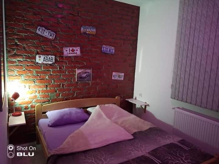 - une chambre avec un mur en briques et un lit dans l'établissement Apartman Ivanović 6, à Sokobanja