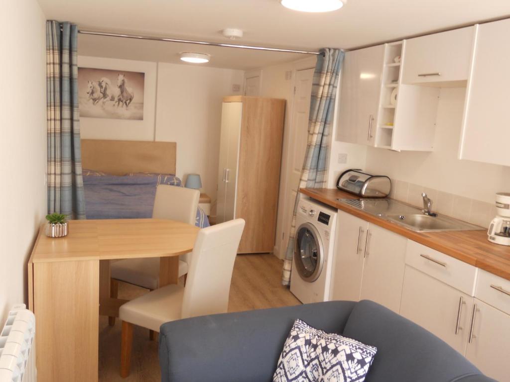 a small kitchen and dining room with a table and a blue couch at The Staithe by the Canal. in Lancaster