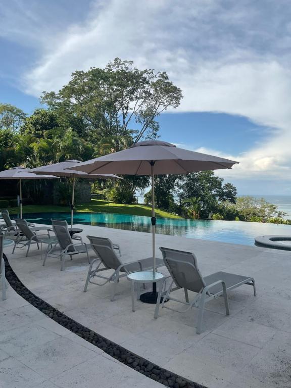 een tafel en stoelen met een parasol naast een zwembad bij Residence Nativa Las Vistas, appartement in Tarcoles
