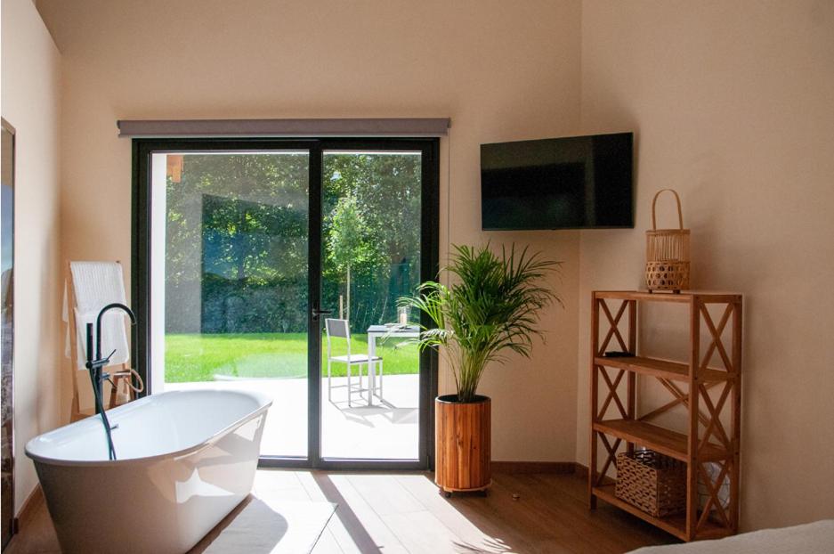 uma casa de banho com uma banheira, uma televisão e uma janela em Las Mareas de Llanes em Andrín
