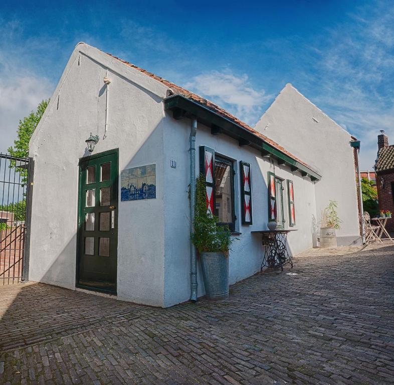 een klein wit gebouw met een groene deur bij Authentiek vakantiehuisje in Terneuzen