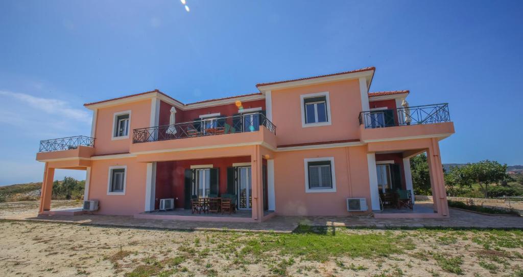 uma casa cor-de-rosa com uma varanda por cima em Agnanti em Xi