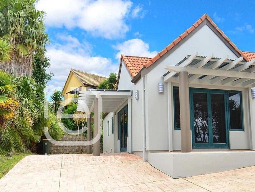 une maison blanche avec une grande porte en verre dans l'établissement Gulf Harbour Guest House Apartment, à Auckland