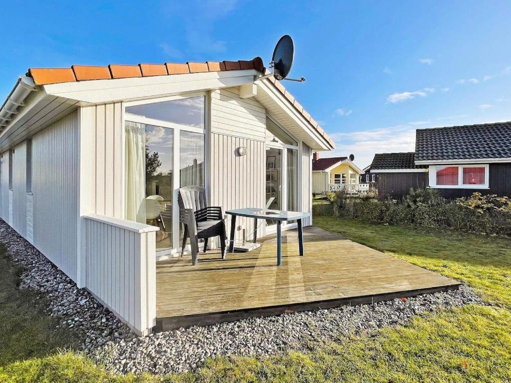 ein kleines Haus mit einer Holzterrasse mit einem Tisch in der Unterkunft 4 person holiday home in GROEMITZ in Grömitz