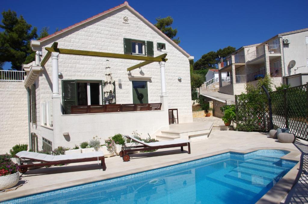 a house with a swimming pool in front of a house at Holiday Home Nevista in Sumartin