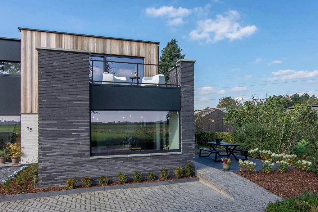a house with a large window on the side of it at Villa veld en velo in Bree