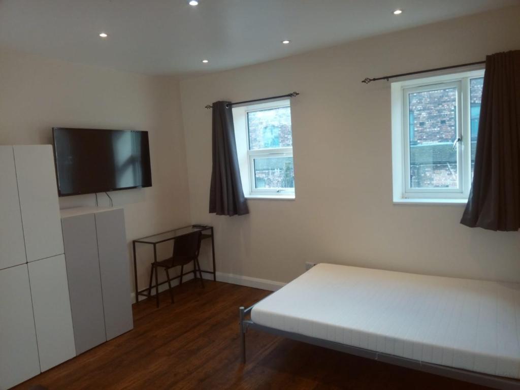 a bedroom with a bed and a flat screen tv at Market Place guest house in Burslem