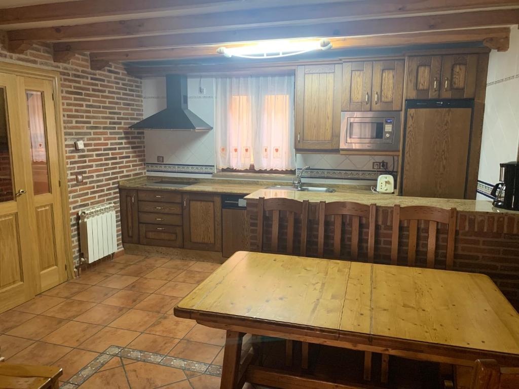 een keuken met houten kasten en een houten tafel bij Casa Rural Los Tasajos in La Horcajada