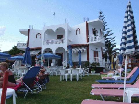 a group of people sitting in lawn chairs in front of a building at Seashell Studios in Argasi