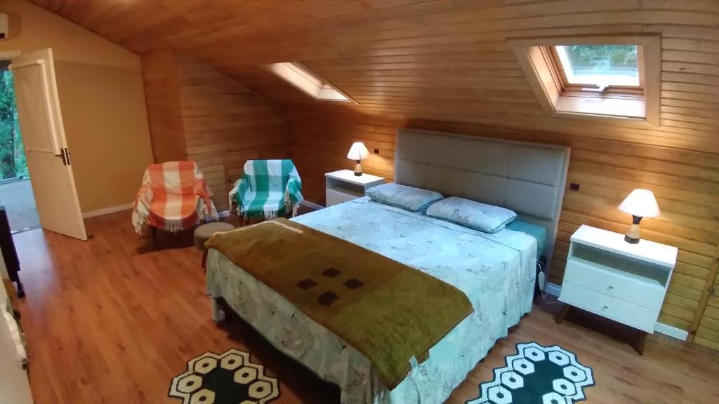 a bedroom with a bed and two chairs in a room at Recanto dos Jasmins Gramado in Gramado