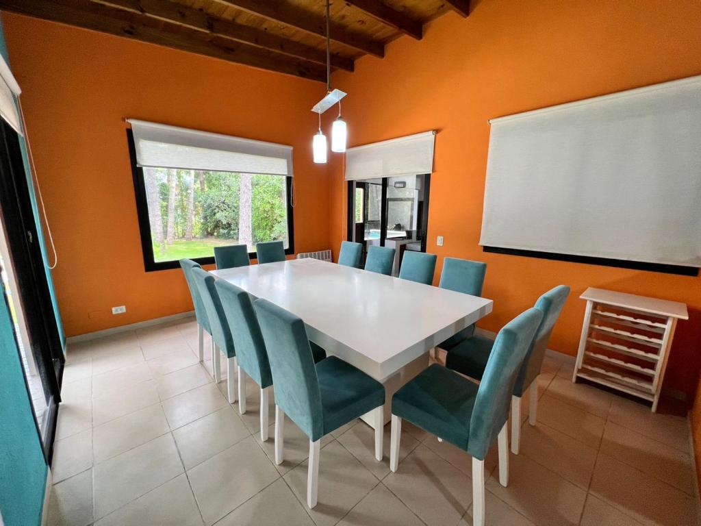 a dining room with a white table and blue chairs at Casa Penelope Pinamar in Pinamar