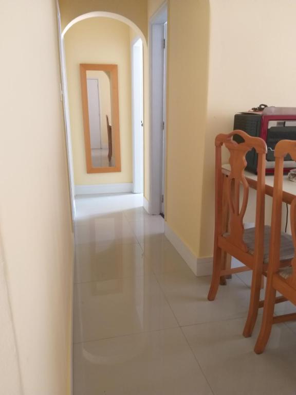 einen Flur mit einem Tisch, einem Stuhl und einem Spiegel in der Unterkunft Apartamento para temporada Ambiente familiar in Santos