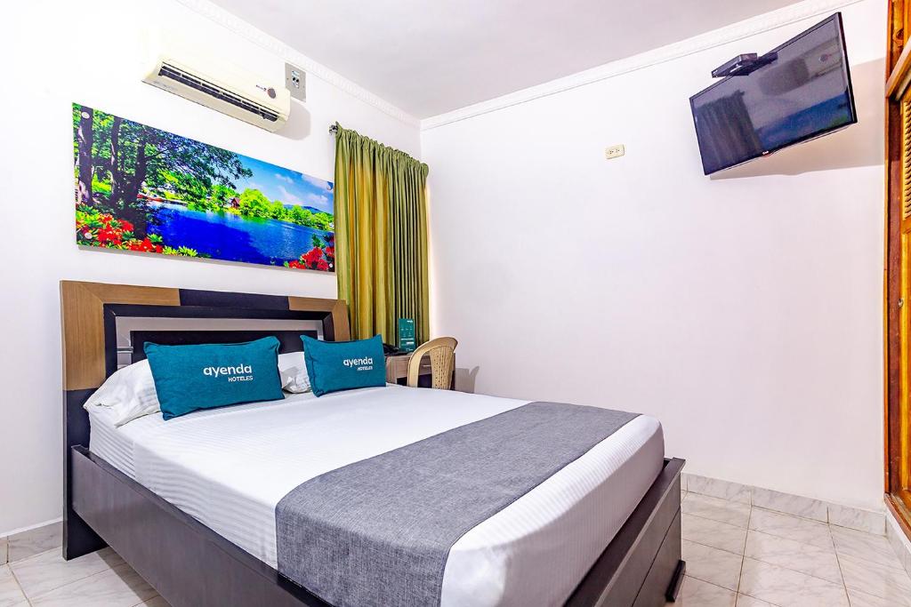 um quarto com uma cama grande e almofadas azuis em Ayenda San Rafael LG em Sincelejo