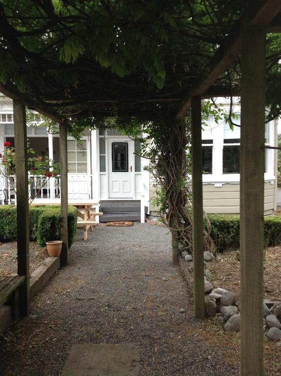 une pergola devant une maison blanche dans l'établissement Aratahi Cottages - West Wing, à Carterton