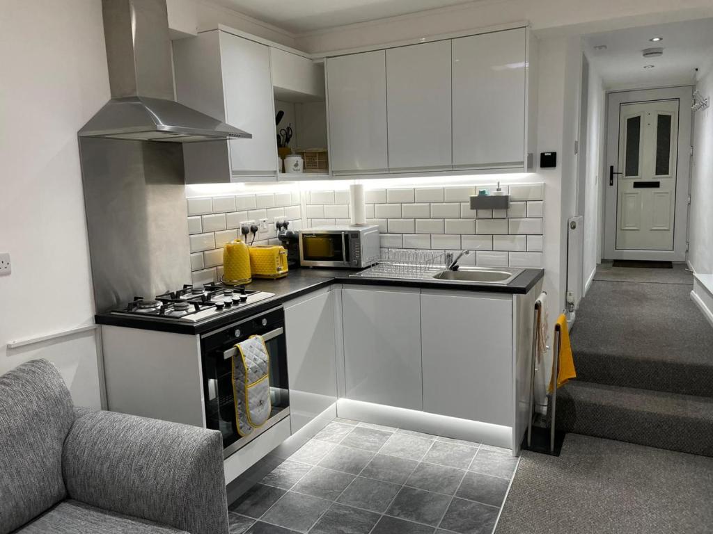 a kitchen with white cabinets and a stove top oven at Balco Sherwood Studio in Nottingham