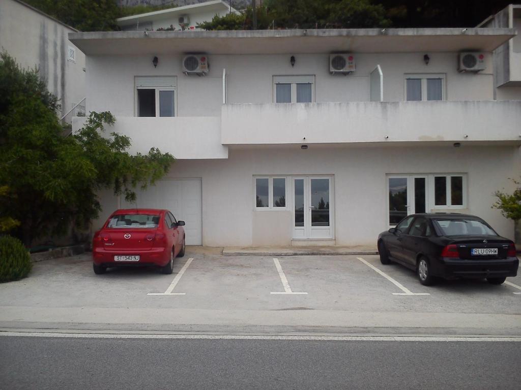 dos autos estacionados en un estacionamiento frente a un edificio en Apartments Filip, en Omiš