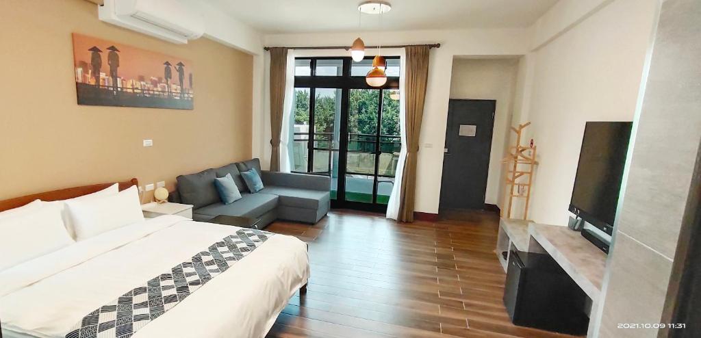 a bedroom with a bed and a couch and a television at 嚨口十二之一民宿Longcall 12-1 in Jinning