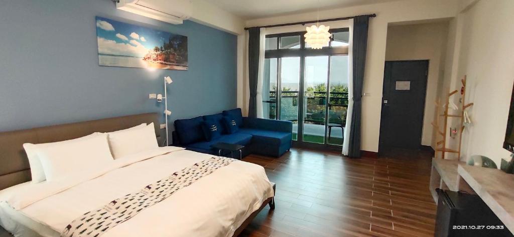 a bedroom with a large bed and a blue couch at 嚨口十二之一民宿Longcall 12-1 in Jinning