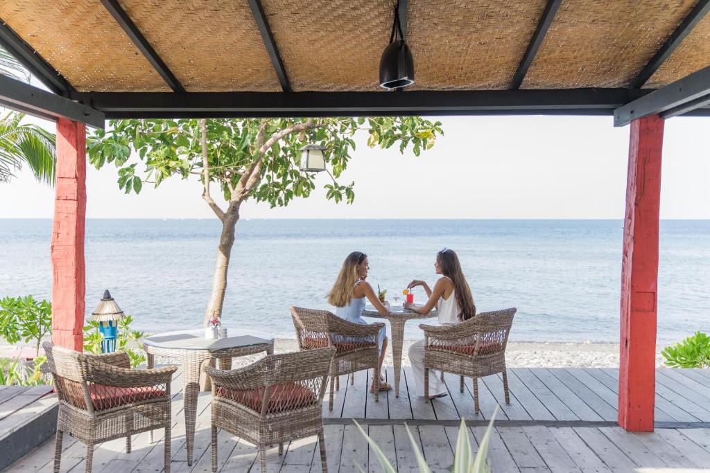 two women sitting at a table on the beach at Amed Lodge by Sudamala Resorts in Amed