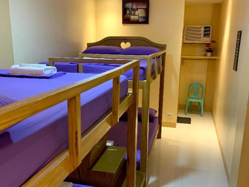 two bunk beds in a room with purple sheets at Susada's Inn in Oslob