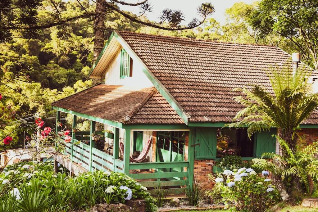 ein kleines grünes Haus mit braunem Dach in der Unterkunft Chalé Memórias 1945, Cascata do Caracol, Canela-RS in Canela