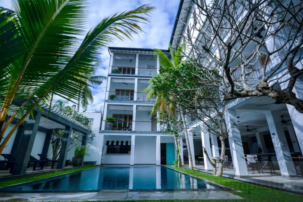 a hotel with a swimming pool in front of a building at Temptation in Hikkaduwa