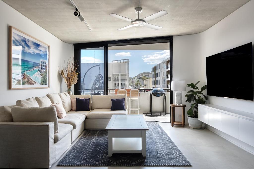 uma sala de estar com um sofá e uma televisão de ecrã plano em Premium Bondi Beach 2 Bedroom with Beach view and parking em Sydney