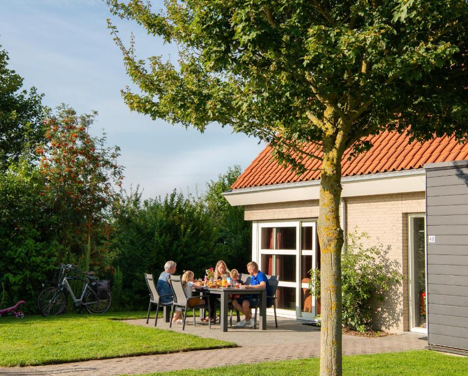 een groep mensen die rond een tafel in een tuin zitten bij Vakantiepark Broedershoek in Koudekerke