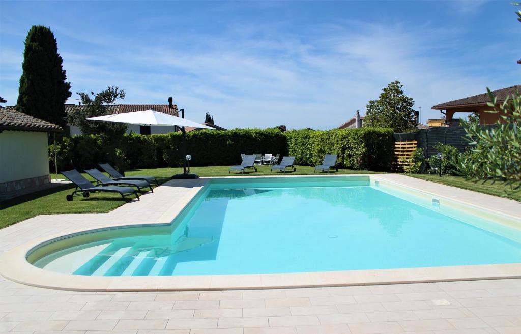 a swimming pool in a yard with chairs and an umbrella at LO SCRIGNO COUNTRY HOUSE in Coltodino