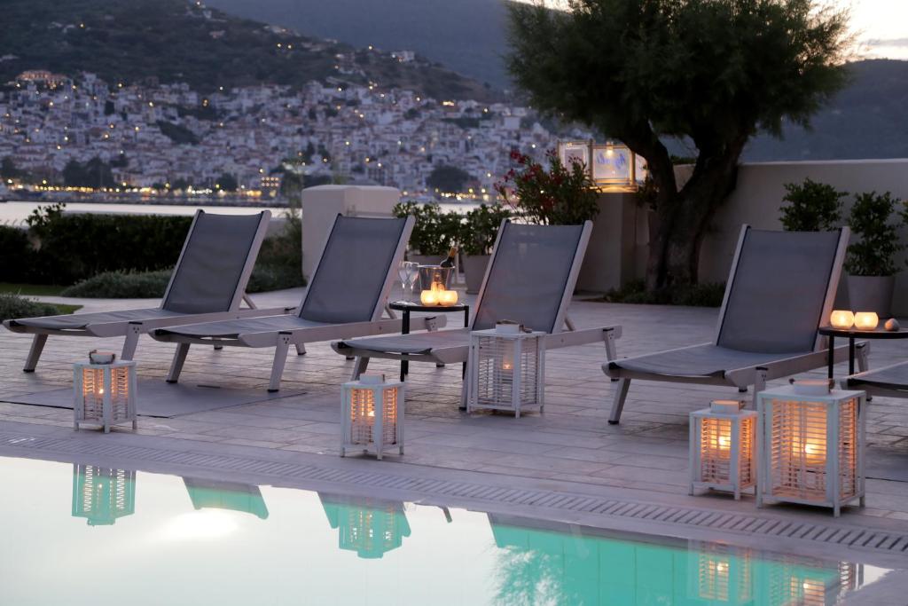 a group of chairs sitting next to a swimming pool at Skopelos Village Hotel in Skopelos Town